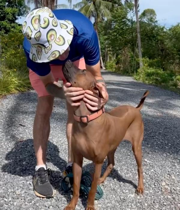 man wearing a hat kissing a rescue dog